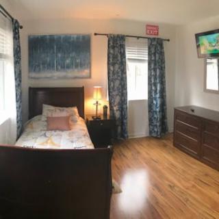 A cozy bedroom with a single bed, wooden flooring, and a wall-mounted TV.