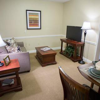 A cozy living room with a sofa, coffee table, TV, and floor lamp.