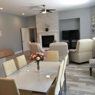 A modern living room with a dining area featuring a fireplace, comfortable seating, and a television.
