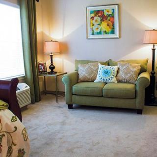 A cozy living room with a green sofa, decorative pillows, and warm lighting from table lamps.