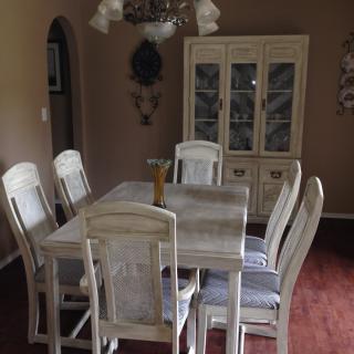 A cozy dining room featuring a rustic table set with six chairs and a glass-front cabinet.