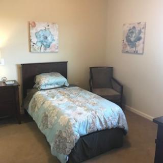 A cozy bedroom featuring a single bed, decorative wall art, and a comfortable chair.