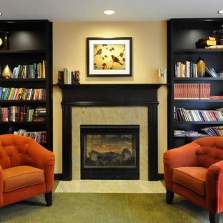 A cozy living room with a fireplace framed by bookshelves and two comfortable armchairs.