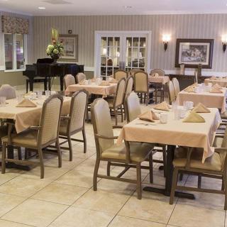 An elegant dining room with neatly arranged tables and a piano in the corner.