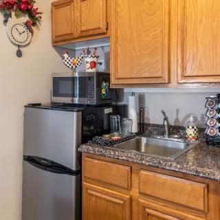 Compact kitchen area with a mini fridge, microwave, and coffee maker on the countertop.