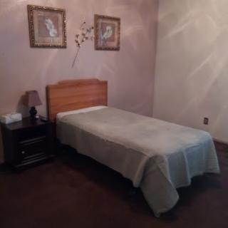 A simple and minimalistic bedroom featuring a single bed and decorative wall art.