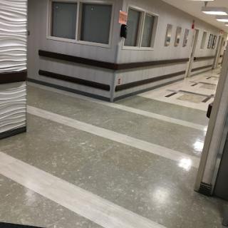 A view of a modern hospital corridor featuring clean lines and a polished floor.