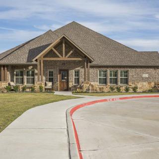 A charming brick house with a spacious driveway and well-maintained lawn.