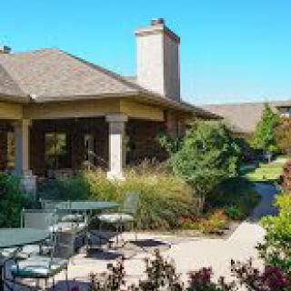 A tranquil outdoor patio surrounded by lush greenery and elegant architecture.