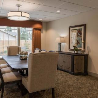 A well-decorated dining room with a large table, upholstered chairs, a sideboard, and elegant lighting.