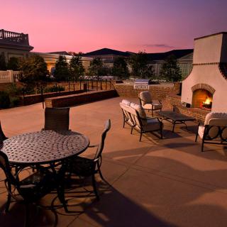 A cozy outdoor patio at sunset, featuring seating and a fireplace.