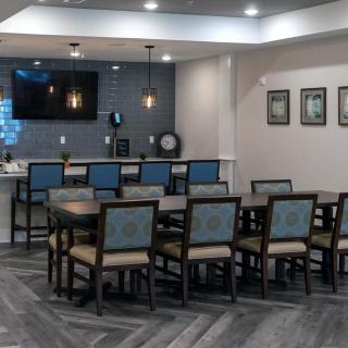 A modern dining or conference area with multiple chairs, a TV on the wall, and stylish lighting.