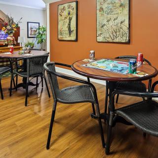 A cozy dining area featuring a table with chairs, displaying drinks and wall art, set against a hardwood floor.