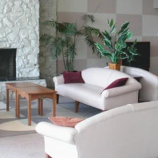 A cozy living room with white sofas, a wooden coffee table, and a stone fireplace.