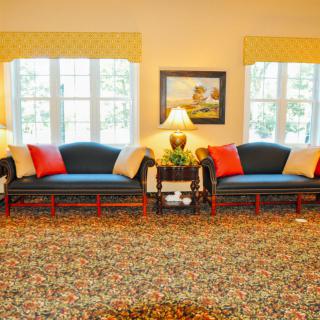 A cozy living room with two sofas, a patterned carpet, and decorative lamps.