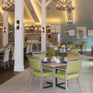 A modern dining area with elegant chandeliers, featuring neatly arranged tables and chairs.