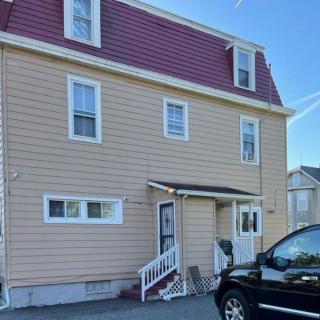 A three-story residential house with a gabled roof and driveway.