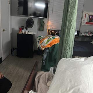 A cozy bedroom setup featuring a television and various items on the bed.