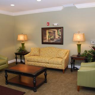 A cozy living room with a yellow sofa, green armchairs, and a wooden coffee table.