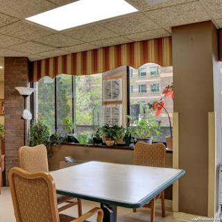 A cozy dining area with plants and natural light streaming through large windows.