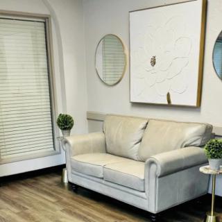 A modern living room with a white couch, decorative mirrors, and minimalist artwork.