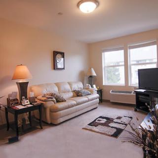 A cozy living room with a sofa, lamps, and a television.