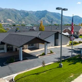 A building with a parking lot and American flag, set against a backdrop of mountains.