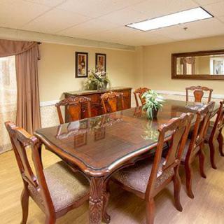 A well-appointed dining room featuring a polished wooden table and chairs, complemented by elegant decor and a large mirror.