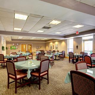 A spacious dining room with neatly arranged tables and chairs, featuring warm lighting and decor.