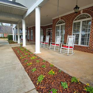 A cozy brick porch with rocking chairs and elegant landscaping.