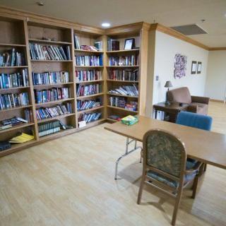 A quiet library space with bookshelves, a table, and chairs for reading.