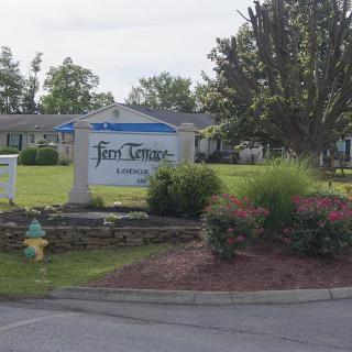 A landscaped area featuring a stone sign surrounded by greenery and flowers.