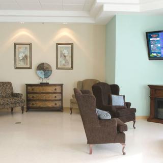 A cozy lobby area featuring comfortable seating, decorative art, and a television.
