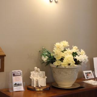 A decorative arrangement with flowers in a vase and various ornaments on a table.