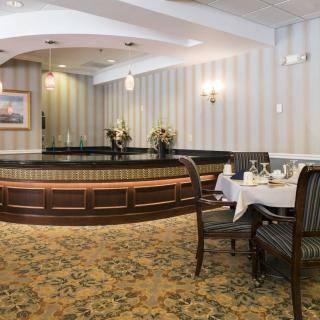 An elegant dining area with tables set for guests, featuring classic decor and floral arrangements.