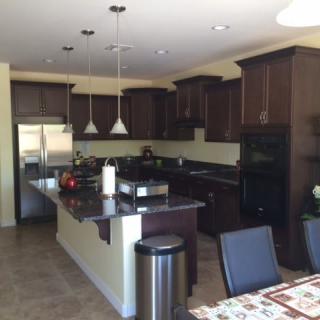 A modern kitchen with dark cabinets, a central island, and stainless steel appliances.