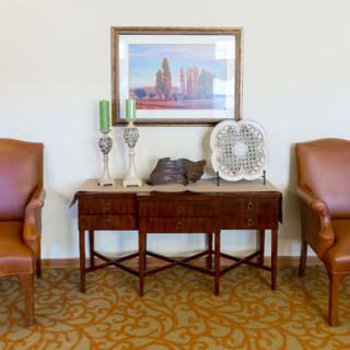 A cozy seating area featuring two leather chairs and a decorated table with a cityscape painting above.
