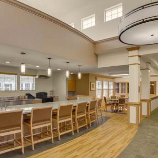 A modern community kitchen and dining area with ample seating and elegant lighting.