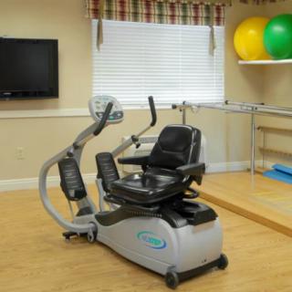 A fitness room featuring a recumbent exercise bike, therapy balls, and a television.