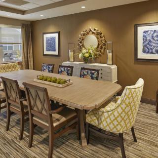 A contemporary dining room with a large wooden table, stylish chairs, decorative artwork, and an elegant mirror.