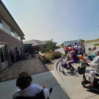 A gathering of seniors enjoying an outdoor social event, with some using wheelchairs and scooters.