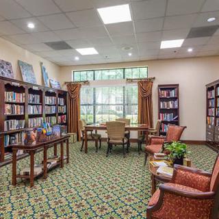 A cozy library room with bookshelves, comfortable chairs, and a large window.