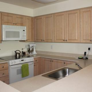A modern kitchen with wooden cabinets, a built-in microwave, and stainless steel appliances.