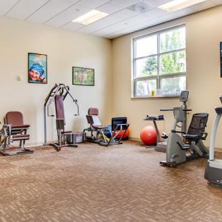 A small gym with various exercise equipment, including bikes and weights.