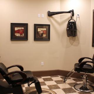 A cozy barber shop featuring black chairs and vintage styling tools, with framed artwork on the walls.