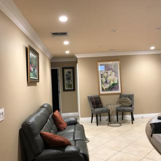 A well-lit living room with artwork, seating area, and modern decor.