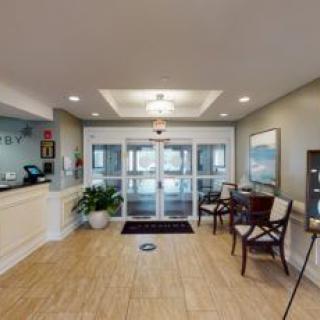 A modern lobby with a reception desk, seating area, and entrance doors.