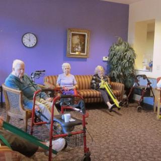 A cozy common area in a nursing home where elderly residents sit and relax with their walkers nearby.
