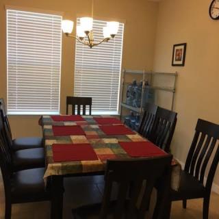 A dining room with a wooden table and chairs, featuring a colorful tablecloth and a chandelier.