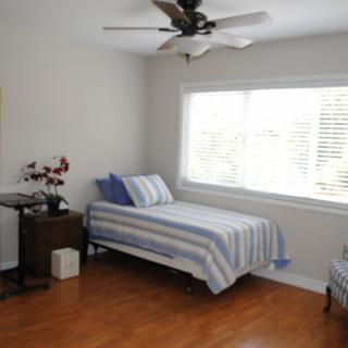A minimalist bedroom with a single bed, striped bedding, and a large window letting in natural light.